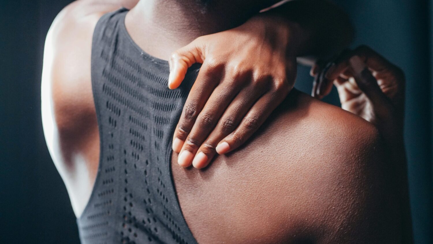person in a black top holding their shoulder