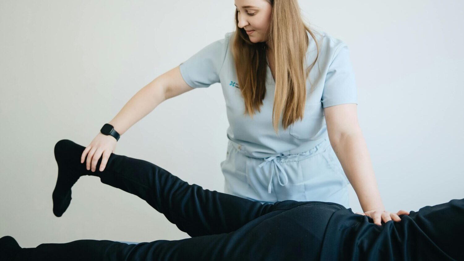 Person in blue scrubs holding a leg up